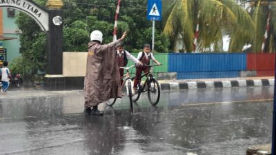 Hujan Tak Halangi Polsek Gerung Atur Lalu Lintas Sekolah